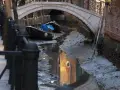 Canali di Venezia quasi asciutti, con barche arenate e riflessi di palazzi. Si vede quanto sono profondi i canali di Venezia in questa situazione insolita.