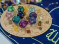 Kości z symbolami zodiaku i numerami 5 i 9, kamienie i talizmany na tle zodiakalnym.
