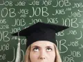 Absolventin mit Doktortitel blickt nach oben, während die Tafel voller "JOB" steht. Die Suche nach Arbeit nach dem Studium ist intensiv.