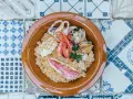 Un saporito cous cous di pesce con gamberi, calamari, cozze e triglia, guarnito con prezzemolo fresco.