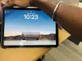 Tablet z włączonym ekranem blokady, widoczny napis "Touch ID" i godzina 10:23. Na ekranie wyświetla się powiadomienie z kodem weryfikacyjnym.
