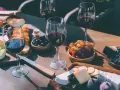 Degustacja wina merlot: jakie to wino? Kieliszki pełne rubinowego trunku, deska serów, winogrona, oliwki i figi tworzą idealną kompozycję.