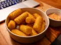 Goldbraune, knusprige Kroketten selber machen ist eine Kunst. Hier sind sie, bereit zum Dippen, neben einer Schüssel mit Sauce.