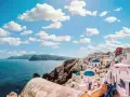 Widok na białe domy z niebieskimi kopułami na greckiej wyspie Santorini nad morzem.