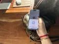 Dłoń trzymająca telefon z aplikacją NFC nad torebką Louis Vuitton.
