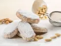 Dolce di Siena cosparso di zucchero a velo, con mandorle e setaccio sullo sfondo.