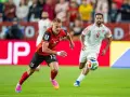 Jugadores de fútbol en acción. El número 15 de Austria corre con el balón, mientras otro jugador se acerca. ¿Quién juega hoy?
