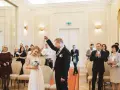 Para młoda świętuje swój ślub cywilny, trzymając się za ręce. W tle widać gości i rodzinę.