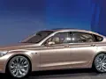 Eleganckie, złote bmw gt z przyciemnianymi szybami i chromowanymi felgami stoi na tle niebieskiej ściany.