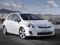 Biała Toyota Auris hybryda na tle miasta. Czy warto zainwestować w ten model?