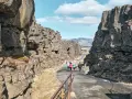 Spacerem przez szczelinę tektoniczną w parku narodowym Þingvellir. Grupa turystów podziwia surowe piękno islandzkiej przyrody.