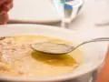 Caldo de pollo casero en un plato blanco con una cuchara.