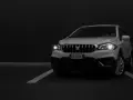 Białe Suzuki SX4 na ciemnym tle, z włączonymi światłami.