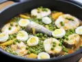 Merluza con guisantes y huevos duros en una sartén. Un plato casero y reconfortante.