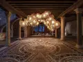 Interni Ca' d'Oro: un lampadario scenografico illumina il cortile con pavimenti a mosaico e colonne antiche.