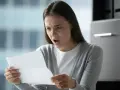 Zaskoczona kobieta czyta dokument, zastanawiając się, czy pracodawca może wysłać na urlop.
