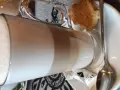 Kawa latte w szklance, obok ciasteczko i cukier. Idealna na przerwę w karczmie u wróbla menu.
