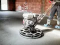 Pracownik wygładza wylewkę styrobetonową za pomocą mechanicznej zacieraczki. Sprawdź aktualną wylewka styrobeton cena za m2.