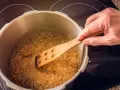 Lentejas deliciosas cocinándose en olla express, removidas con cuchara de madera.