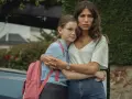 Erin Carter abbraccia una bambina con uno zaino rosa. La donna sembra preoccupata, la bambina protetta.
