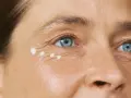 Augenpartie einer Frau über 40 mit feinen Linien und aufgetupfter Creme.