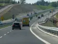 Droga ekspresowa z samochodami i motocyklami, gdzie panuje bezpieczna prędkość. W tle widać prace budowlane.