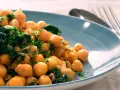 Garbanzos salteados con espinacas y ajo, una de las muchas recetas con garbanzos de bote, servidos en plato azul.
