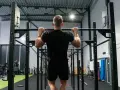 Man tränar pull ups i ett modernt gym.