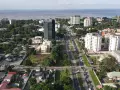 Widok z lotu ptaka na nowoczesne miasta w Afryce, z wysokimi budynkami, zielenią i ruchliwą drogą w tle.