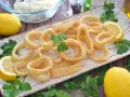 Calamares a la andaluza crujientes y dorados, servidos con limones frescos y perejil.