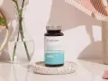 Flacon de cure de collagène marin Novoma, posé sur un plateau décoratif, près d'un miroir, d'une fleur et d'une brosse à dents.