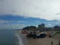 Chłopy trasa: łodzie rybackie na plaży, budynek z czerwonym dachem, morze i niebo z chmurami.