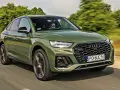 Zielone Audi Q5 Sportback z silnikiem 50 TFSI jedzie po drodze. Kierowca w okularach przeciwsłonecznych prowadzi auto.