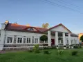 Elegancki pałac w Korczewie z kolumnowym portykiem i kamienną podmurówką, otoczony zadbanym ogrodem.