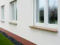 Eleganckie, kamienne parapety przy białym domu. Zastanawiasz się, jak przedłużyć parapet? Ten przykład pokazuje, jak estetycznie można to zrobić.