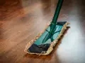 Mopa limpiando un suelo de parquet. Descubre remedios caseros para reparar parquet y mantenerlo como nuevo.