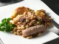 Un plato de el cassoulet con pollo crujiente, salchicha y perejil fresco.