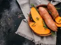 Pomarańczowe bataty, pokrojone i w całości, ozdobione ziołami. Ich bogate bataty wartości odżywcze czynią je idealnym składnikiem zdrowej diety.