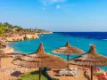 Piękna plaża w Sharm El Sheikh z turkusową wodą i palmami. Czy w Sharm el Sheikh jest bezpiecznie? Tak, to popularny kurort turystyczny.