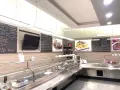 Interior of a restaurant with a display counter, menu boards, and food images.