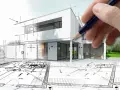 Dłoń trzyma ołówek nad szkicem nowoczesnego domu, który przechodzi w wizualizację. Architekt tworzy marzenie.