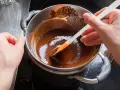 Delikatne mieszanie rozpuszczonej czekolady w kąpieli wodnej, by uzyskać idealną konsystencję.
