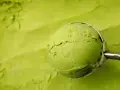 Eine Kugel cremiges Matcha-Eis wird mit einem Löffel aus einer Schüssel gehoben. Perfekt für ein erfrischendes Matcha Eis Rezept.