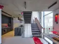 Nowoczesne wnętrze z betonowym sufitem i schodami. W kuchni czarne meble, a na podłodze gładka mikrocement podłoga.
