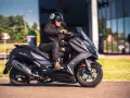 Mężczyzna w kasku jedzie na skuterze Kymco Downtown 125. Poznaj kymco downtown 125 dane techniczne.