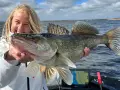 Glückliche Anglerin präsentiert stolz einen großen Zander, gefangen beim Jig-Angeln.