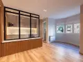 Entrada salón recibidor integrado. Cocina moderna con cristalera y madera, conectada a un luminoso salón con ventanas.