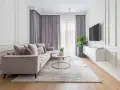 Elegancki salon w stylu modern classic. Jasna sofa, okrągły stolik kawowy, dywan i zasłony tworzą przytulną atmosferę.