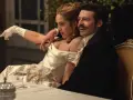 Elegancka para przy stole, zapowiedź nowych produkcji Netflix. Kobieta w białej sukni z rękawiczkami, mężczyzna w czarnym fraku.