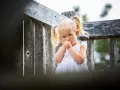 Mała dziewczynka z blond kucykami ssie kciuk, co może być sygnałem, że rodzice zastanawiają się, jak oduczyć dziecko ssania kciuka.